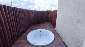A hot tub in a narrow outdoor space with a wooden fence on one side and a concrete wall on the other. - Max Carneiros Suites - Com e sem Piscina Privativa (Tamandaré)