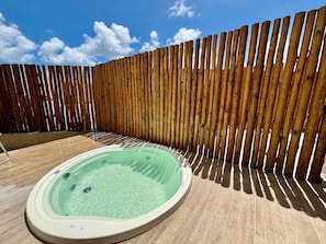 A hot tub in a backyard with a wooden fence and a clear sky. - Max Carneiros Suites - Com e sem Piscina Privativa (Tamandaré)