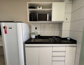 Una cocina funcional con refrigerador, microondas, pileta y cocina a gas.