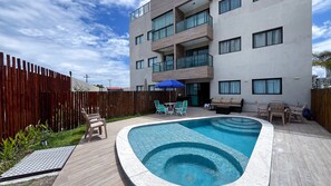 A modern apartment building with a swimming pool, outdoor seating, and a wooden fence. - Max Carneiros Suites - Com e sem Piscina Privativa (Tamandaré)