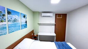 A hotel room with a bed, a nightstand, a wall-mounted air conditioner, and a door. - Max Carneiros Suites - Com e sem Piscina Privativa (Tamandaré)