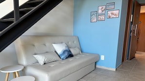 A modern living room with a sofa, two small tables, and a staircase. - Max Carneiros Suites - Com e sem Piscina Privativa (Tamandaré)
