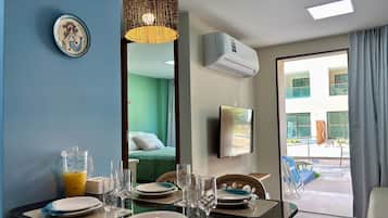 Uma sala de jantar com uma mesa posta para quatro pessoas, um espelho grande e um aparelho de ar condicionado na parede.
