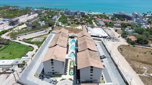 A large hotel with two prominent buildings, a swimming pool, and a beachfront view. - Max Carneiros Suites - Com e sem Piscina Privativa (Tamandaré)