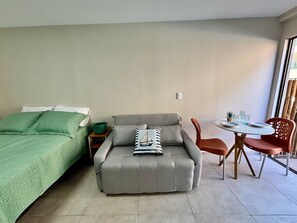 Una stanza con un letto, un divano, un tavolino e sedie.