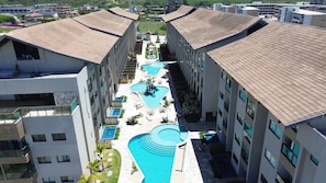 Un hôtel à plusieurs étages doté d’une piscine centrale, de plusieurs petites piscines et d’espaces de détente en plein air.
