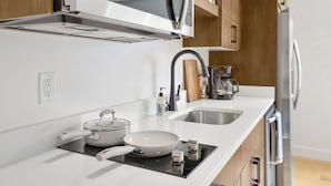 Een moderne keuken met een ingebouwde magnetron, fornuis en spoelbak.