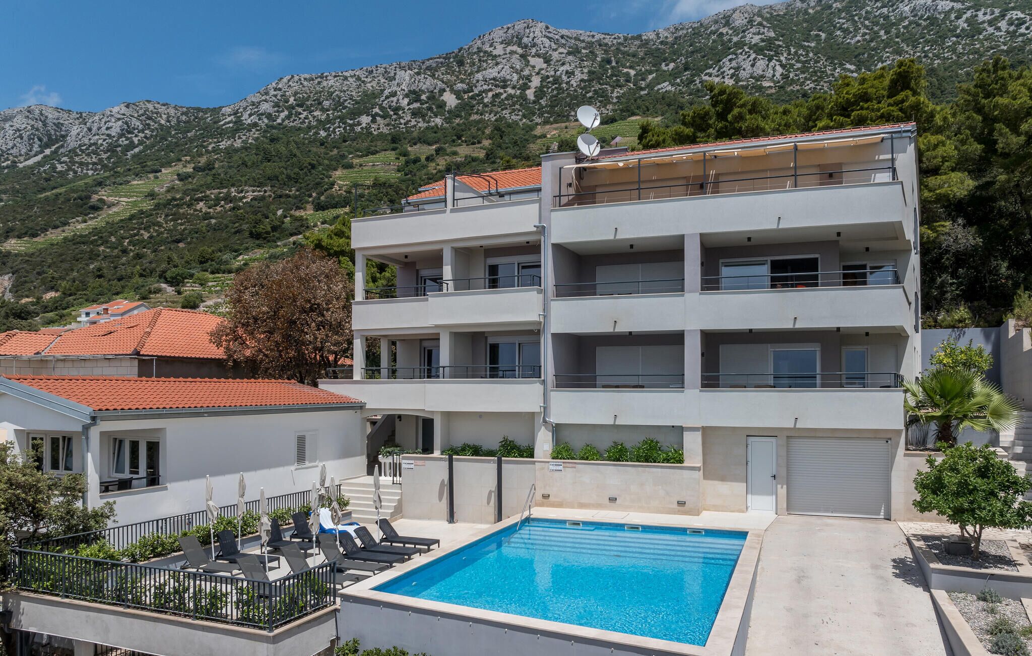 Un edificio de varios pisos con piscina, balcones y vistas a un paisaje montañoso.