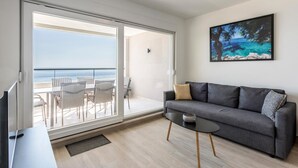 A modern living room with a grey sofa, a small black table, and a TV. - Gorgeous apartment in Dingac with swimming pool (Dingac)
