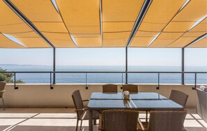 Terraço com mesa de vidro e cadeiras de vime, com vista para um corpo d'água.