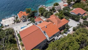 Zona residencial a la costa, amb cases amb teulades vermelles, una platja i una vista clara del mar.