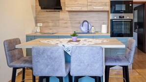 Una cocina compacta con una isla central, dos taburetes de bar, un fregadero y un horno Bosch.