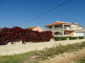 Uma casa de dois andares com varanda, garagem e um jardim bem cuidado.