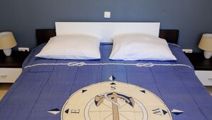 A bed with a blue bedspread featuring a compass design, two white pillows, and a white headboard. - Apartments Jurić - One Bedroom Apartment With Terrace (Plavi) (Kali)