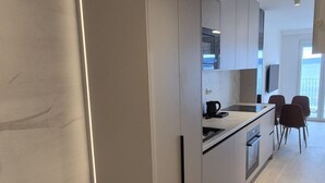 Cozinha moderna com forno embutido, cafeteira e uma janela grande.