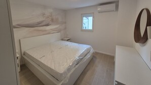 Quarto com cama, janela e ar condicionado fixado na parede.