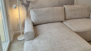 Uma sala de estar moderna com um sofá seccional, um abajur e um mural na parede.