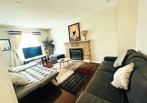 Una sala de estar con un sofá, un televisor, una chimenea y un cuadro en la pared.