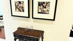 Two framed artworks on a wall, a small wooden table with a metal frame in front. - Luxury 4BR Home Near Square One, with King Bed (Mississauga)