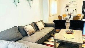 A living room with a grey sofa, a wooden coffee table, and a dining area with chairs and a table. - Luxury 4BR Home Near Square One, with King Bed (Mississauga)