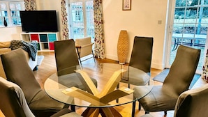 Un salon moderne avec une table basse en verre, des fauteuils en cuir, un canapé et un téléviseur à écran plat.