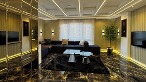 Una sala de estar moderna con un sofá de cuero negro, una mesa de centro de vidrio y una planta en maceta.