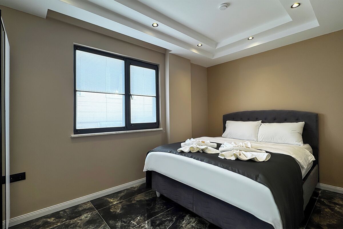A bedroom with a large bed, a window, and a ceiling with recessed lighting.