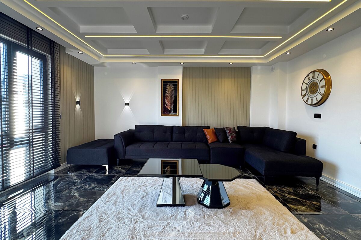 Una sala de estar moderna con un sofá modular, una mesa de centro de vidrio y un espejo grande.