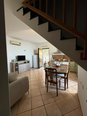 Uma cozinha com mesa de jantar, cadeiras e escada que leva a outro andar.