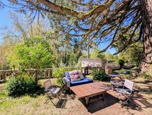 An outdoor seating area with a stone bench, a wooden table, and two folding chairs. - La Chambre Royale - Domaine de la Dordrona (Bourdeilles)