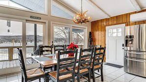 A dining area with a view of Seymour Lake, a wooden-paneled wall, and a stainless steel refrigerator. - Seymour Lake Across St! Scenic Home w/ Hot Tub (Morgan)