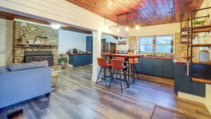 Une cuisine spacieuse avec une cheminée en pierre, un plafond en bois et un coin bar avec des tabourets.