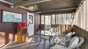 A wooden interior with a glass table, wicker chairs, and a painting on the wall.