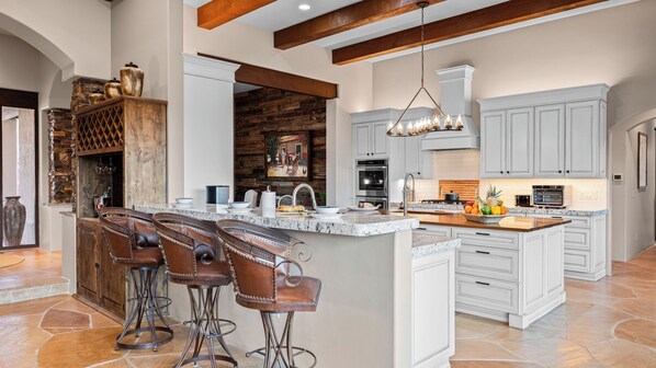 A spacious kitchen with a large island, bar stools, and modern appliances. - 5bdr Oasis w/ Waterfall Pool, Hot Tub, Desert View Desert Cascase by Avantstay (Carefree)