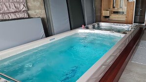 Ein rechteckiges Whirlbad mit einer Holzdielen-Terrasse und gefliestem Boden.