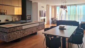 Eine moderne Küche mit einer Kochinsel, einem Essbereich mit Tisch und Stühlen sowie einem Wohnbereich mit Sofa und Vorhängen.