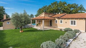 Una casa de dues plantes amb teulada de rajola, terrassa coberta i piscina.