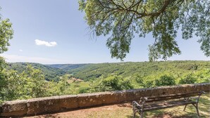 Un banc amb vista a un paisatge amb zones boscoses i un cel serè.