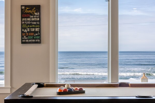 Een biljarttafel met uitzicht op de oceaan door een groot raam.