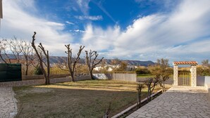 A courtyard with a stone pathway, a small gate, and a view of distant buildings and mountains. - 2 bedroom lovely apartment in Pag (Pag)