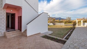 A modern house with a white exterior, a red door, and a staircase leading to a covered porch. - 2 bedroom lovely apartment in Pag (Pag)