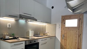 Une cuisine moderne avec des armoires blanches, un four encastré et une porte en bois.