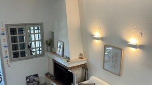 Un salon avec une cheminée, un canapé blanc, une table basse et un élément décoratif en pierre sur un mur.