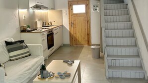 Un espace de vie compact comprenant un coin cuisine, un canapé, une table basse et un escalier.