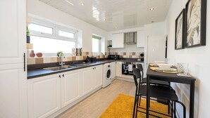 A modern kitchen with white cabinets, a built-in oven, and a dining area with a table and chairs.
