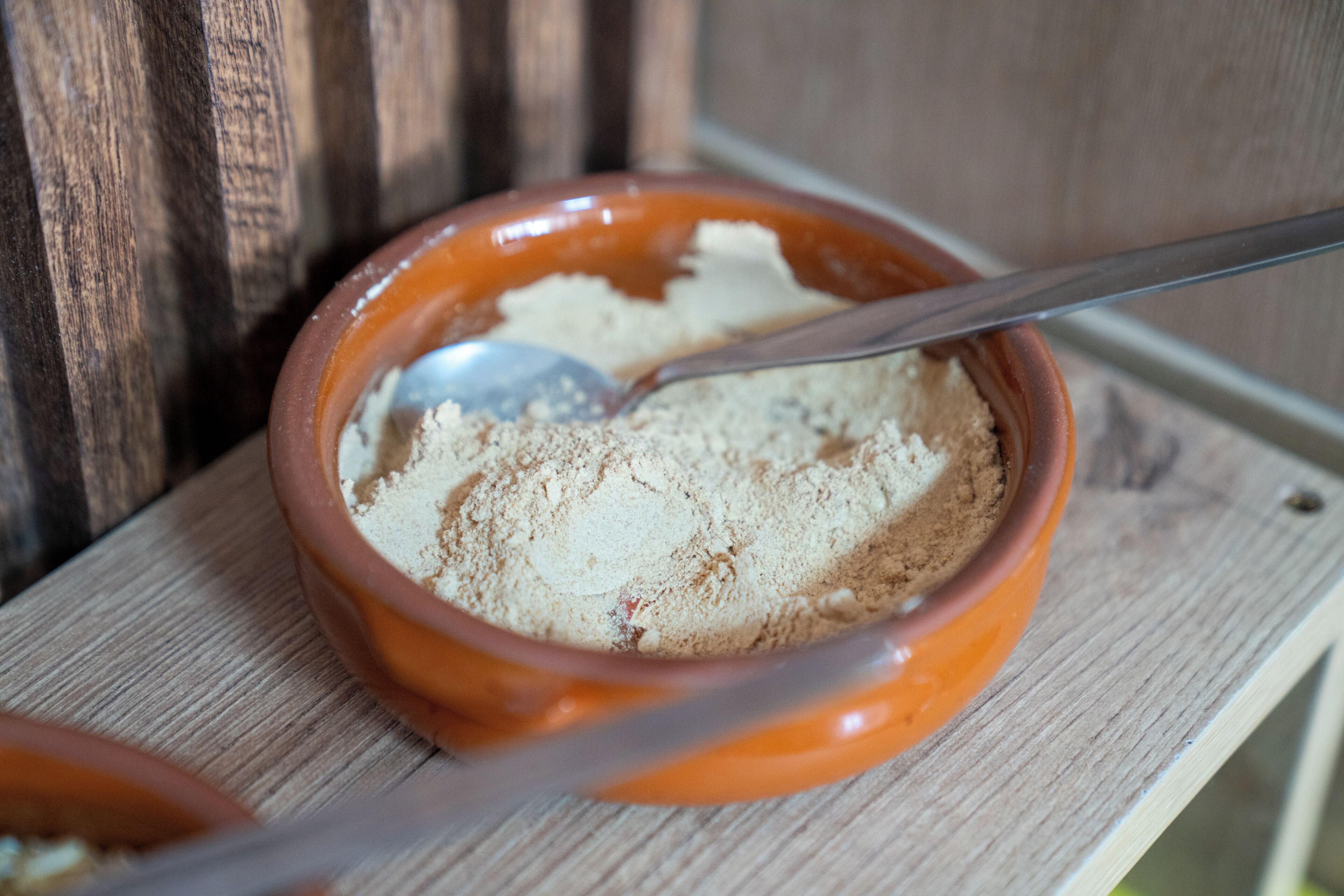 A bowl of dry, crumbly food on a wooden surface.