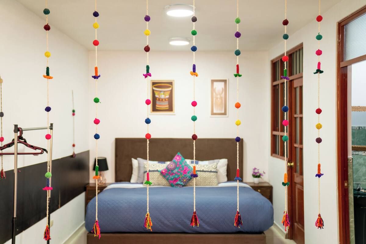 A neatly arranged bedroom with a bed, pillows, a nightstand, and a hanging decoration.