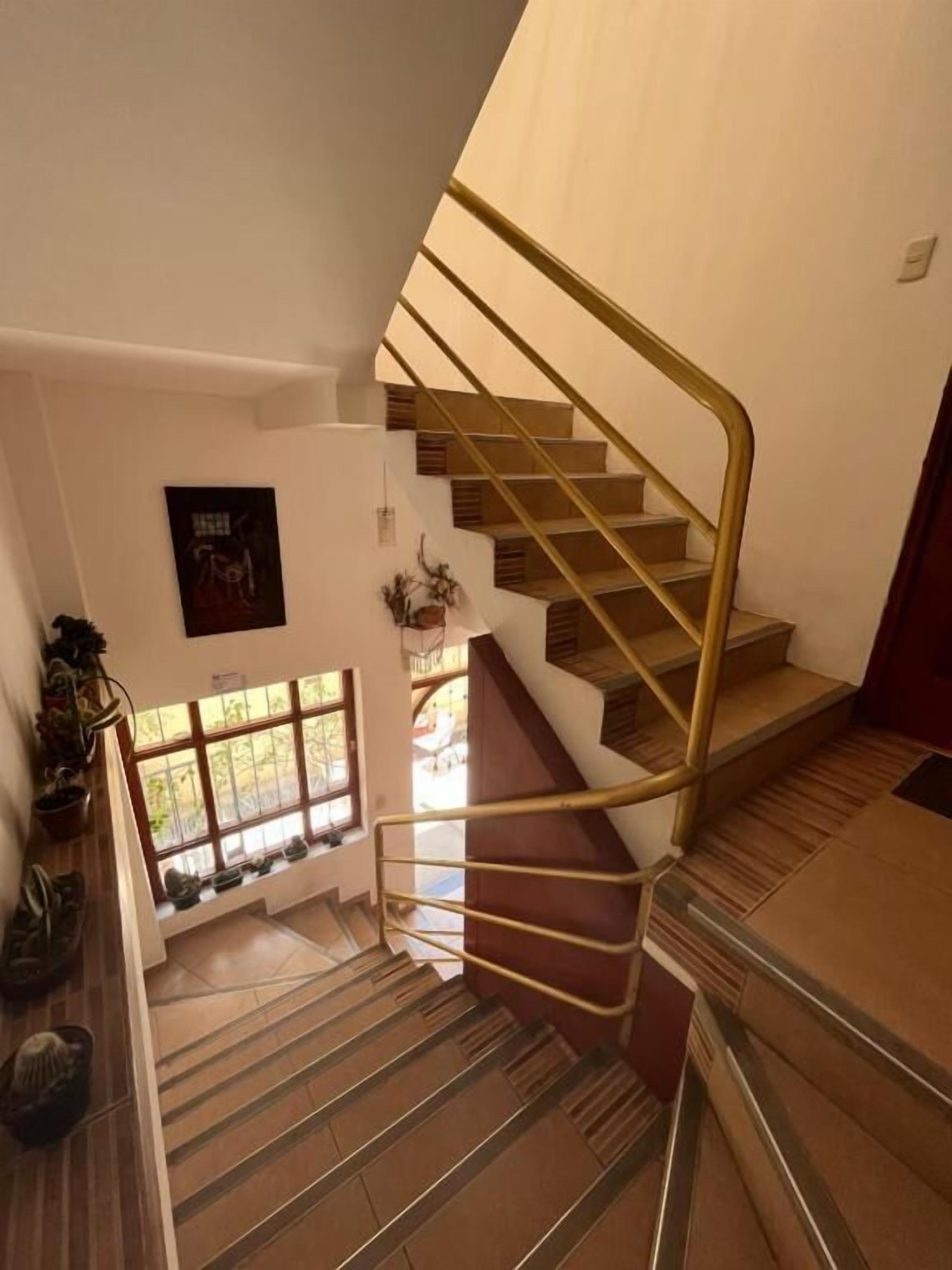 A staircase with a wooden handrail and steps, leading to an upper floor.