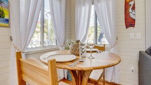 Una mesa de madera con mantel blanco, dispuesta con platos, cubiertos y cristalería.