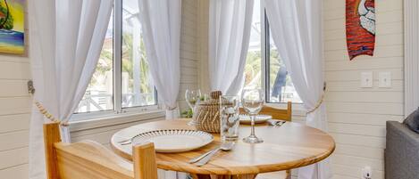 Una mesa de madera con mantel blanco, dispuesta con platos, cubiertos y cristalería.